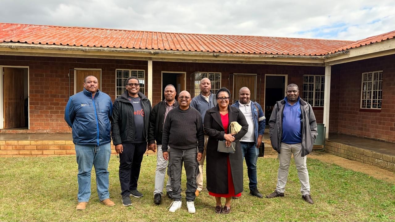 Members of the council standing together in front of a brick building with a red roof